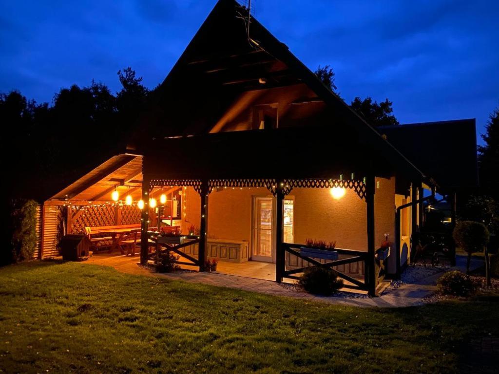 a house with a lit up patio at night at Szmaragdowy domek in Nowy Wiśnicz