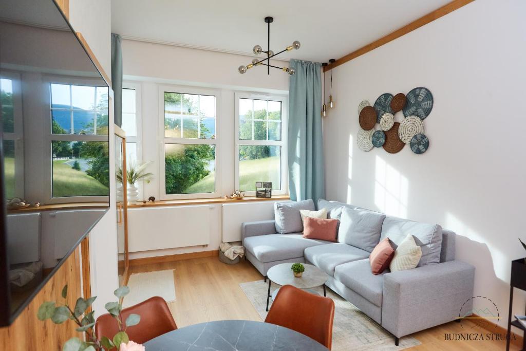 a living room with a couch and some windows at Apartament Budnicza Struga z Sauną i Parkingiem - 5D Apartamenty in Karpacz