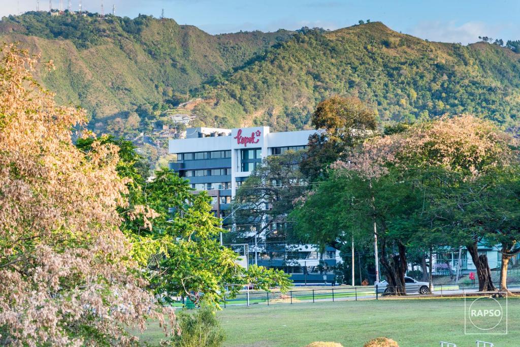 a large white building in front of a mountain at Kapok Hotel in Port-of-Spain