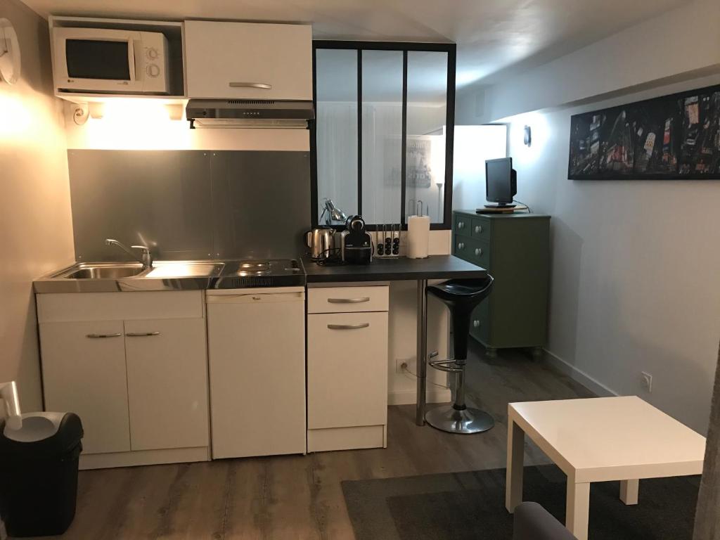 uma cozinha com armários brancos, um lavatório e uma mesa em Joli Studio/T1 Rennes em Rennes
