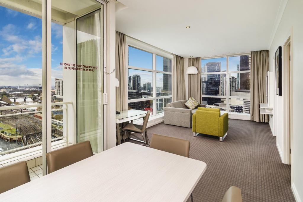 a living room with a table and chairs and windows at Clarion Suites Gateway in Melbourne