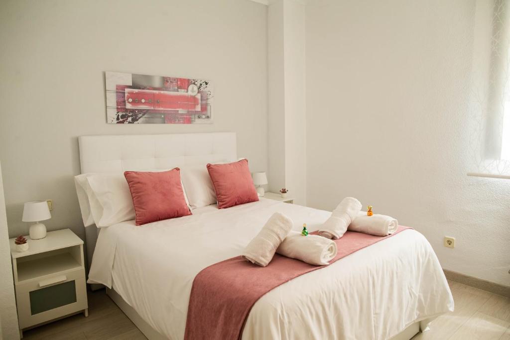 a bedroom with a white bed with pink pillows at Toledo Enamora con Garaje in Toledo