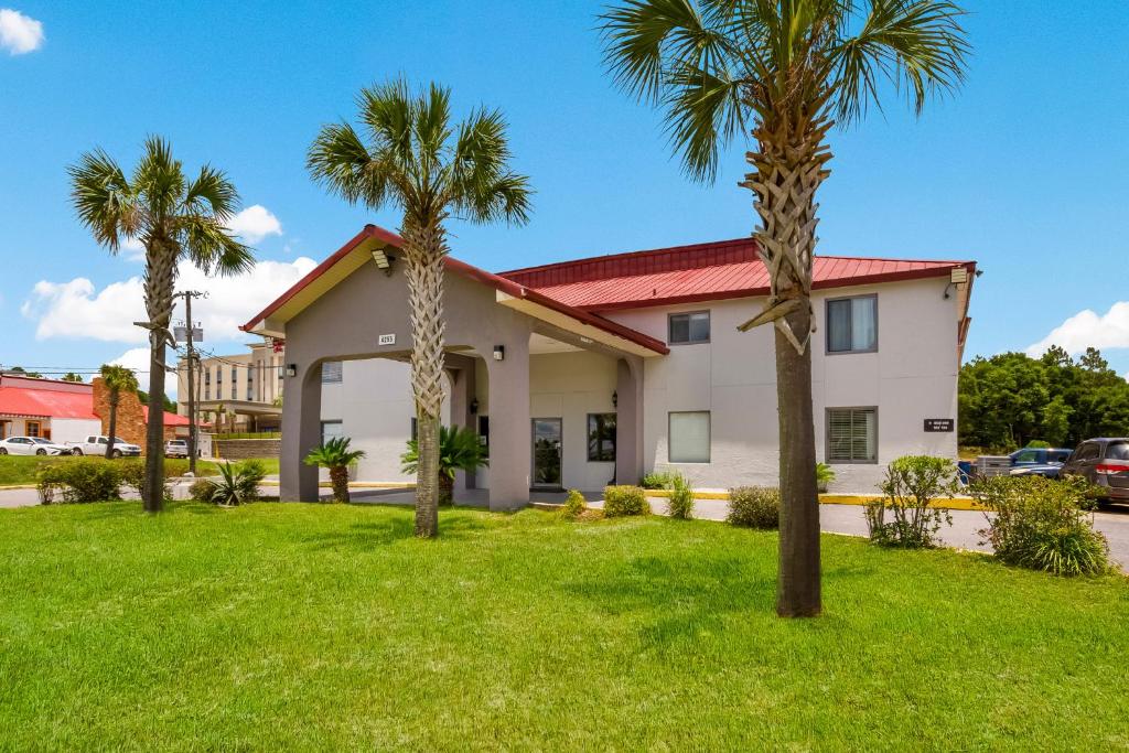 a house with palm trees in the front yard at Red Roof Inn Crestview in Crestview