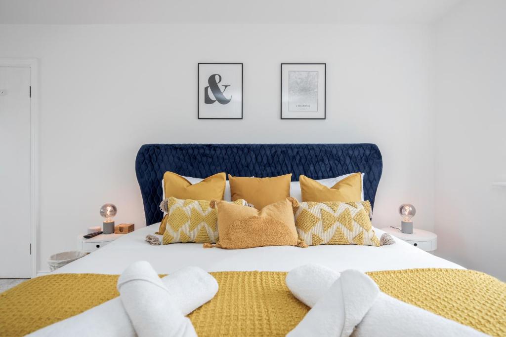 a bedroom with a large bed with yellow pillows at Large Penthouse by Damask Homes with Parking in Redbridge