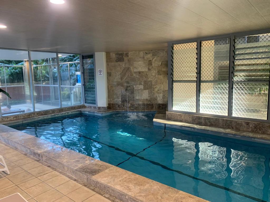 a large swimming pool with blue water and windows at 40 William Street Apartments in Port Macquarie