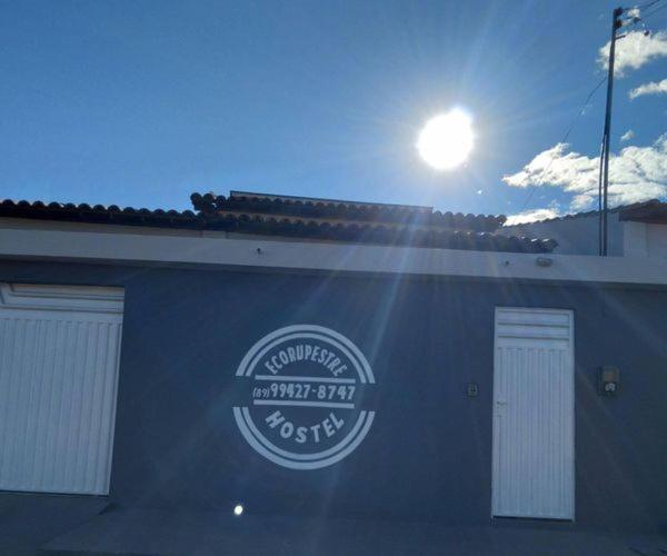 a blue building with the sun shining behind it at EcoRupestre Hostel & Receptivo in São Raimundo Nonato
