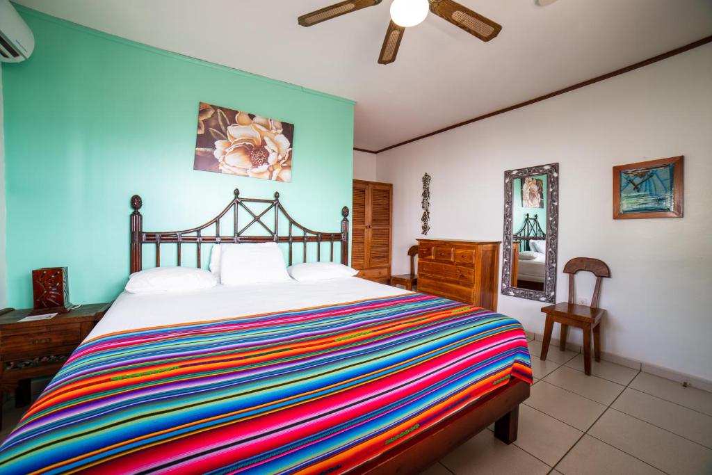 a bedroom with a bed with a colorful striped blanket at Splash Inn Dive Resort & Villas in West End