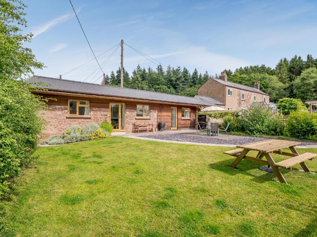 uma cabana de madeira com uma mesa de piquenique no quintal em The Stable Rose Cottage em Yorkley