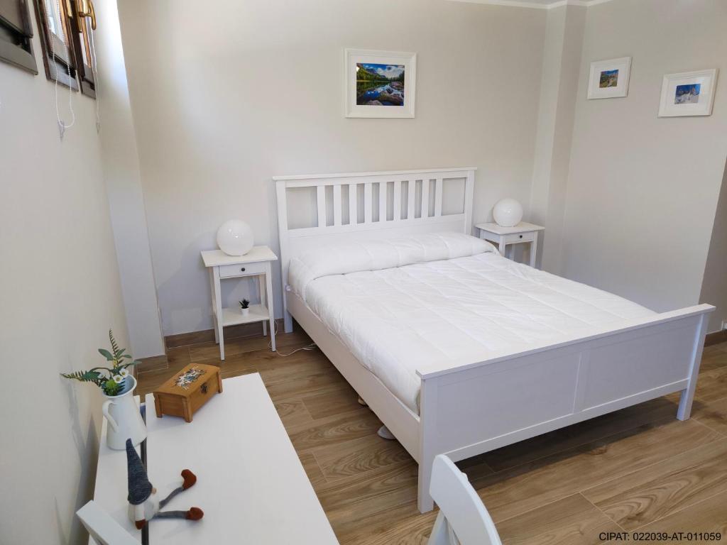 - une chambre blanche avec un lit blanc et 2 tables dans l'établissement Pordoi H10, à Alba di Canazei