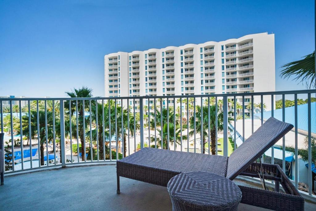 un balcón con mesa y silla y un edificio en Palms Resort #1405 Jr 2BR en Destin