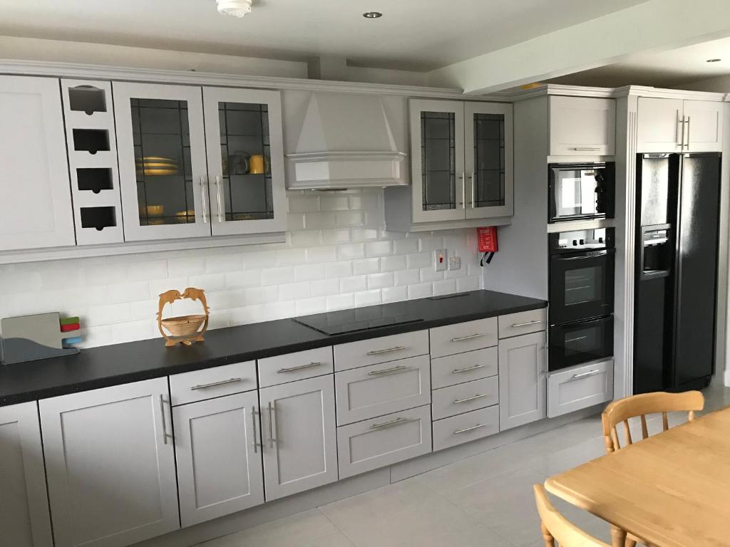 a kitchen with white cabinets and a black refrigerator at Mourne country cottage in Warrenpoint