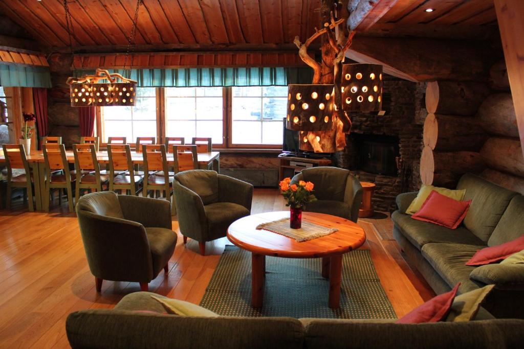 a living room with couches and a table and a fireplace at Rukanhelmi Cottage in Ruka