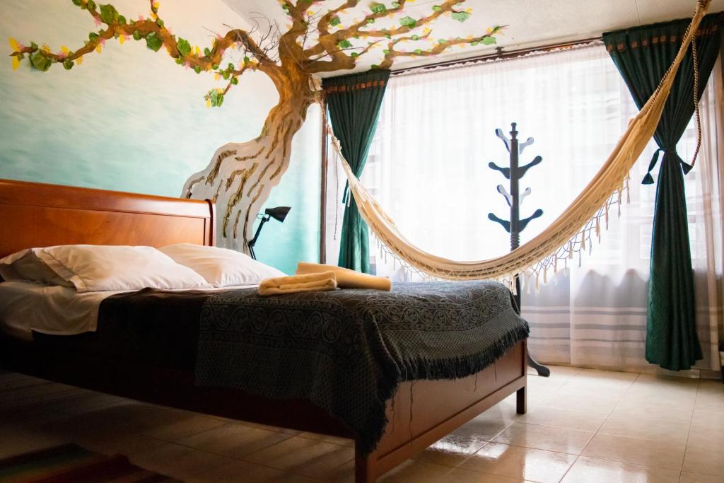 1 dormitorio con 1 cama con un árbol en la pared en Casa Mood Usaquen, en Bogotá