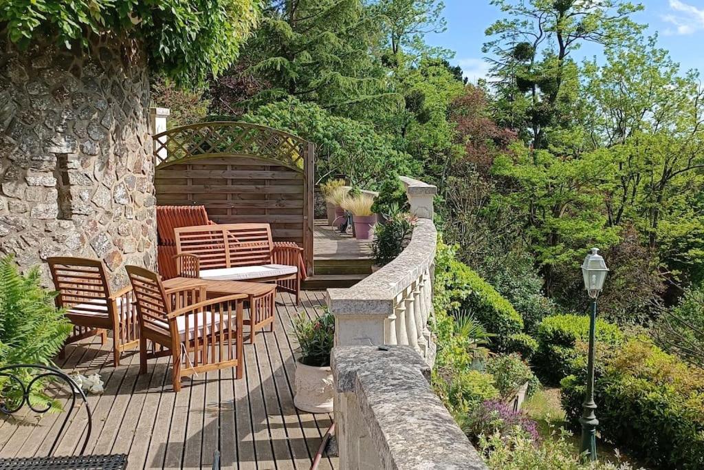 een patio met stoelen, een tafel en een stenen muur bij Gîte atypique vue panoramique in Montrevault