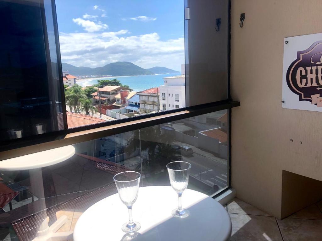 dos copas de vino sentadas en una mesa frente a una ventana en Apto Ingleses Mar, en Florianópolis