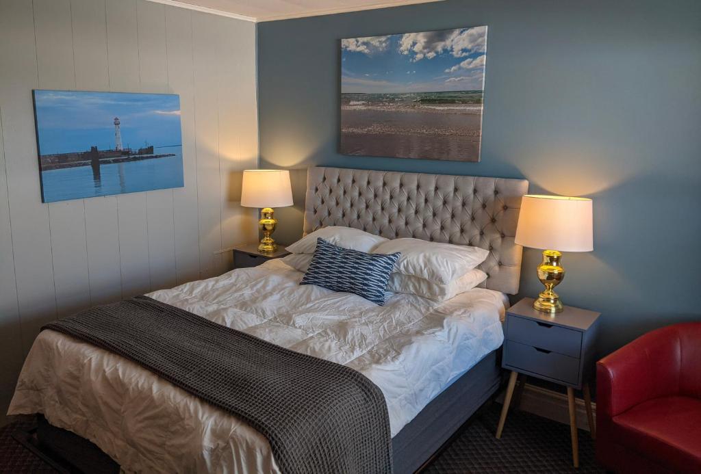 a bedroom with a bed with two lamps and a red chair at Huron Inn in Saint Ignace