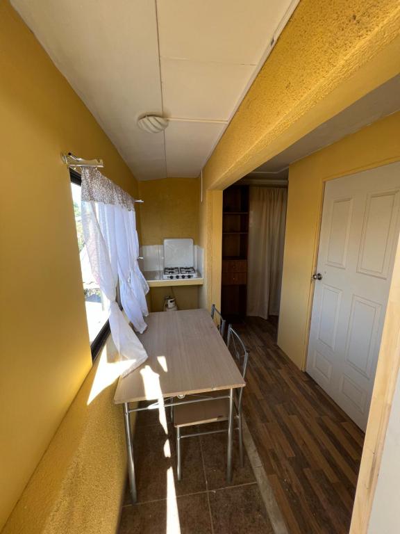 Habitación con mesa y cocina con paredes amarillas. en alojamiento diario con baño compartido, en Calama