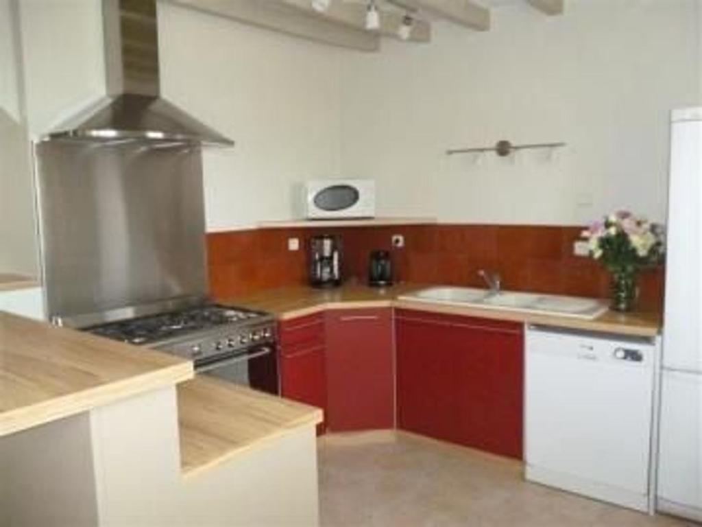a kitchen with red cabinets and a stove top oven at Gîte Saint-Christophe-en-Champagne, 5 pièces, 8 personnes - FR-1-410-192 in Saint-Christophe-en-Champagne