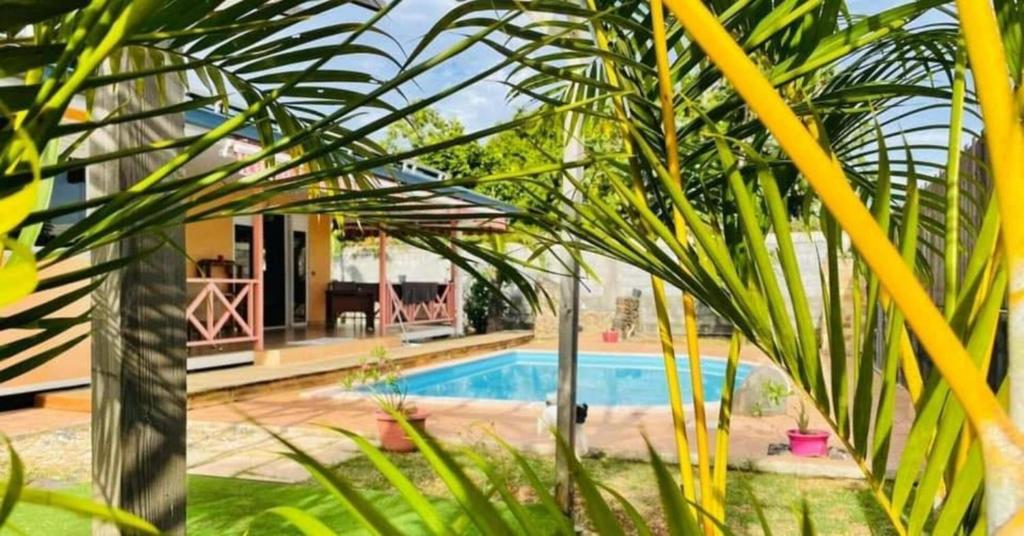 una casa con piscina e alcune palme di TAHITI - Fare Vairai Pool a Faaa