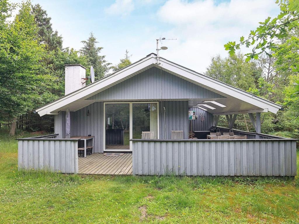 una pequeña casa gris con terraza de madera en 5 person holiday home in lb k, en Ålbæk