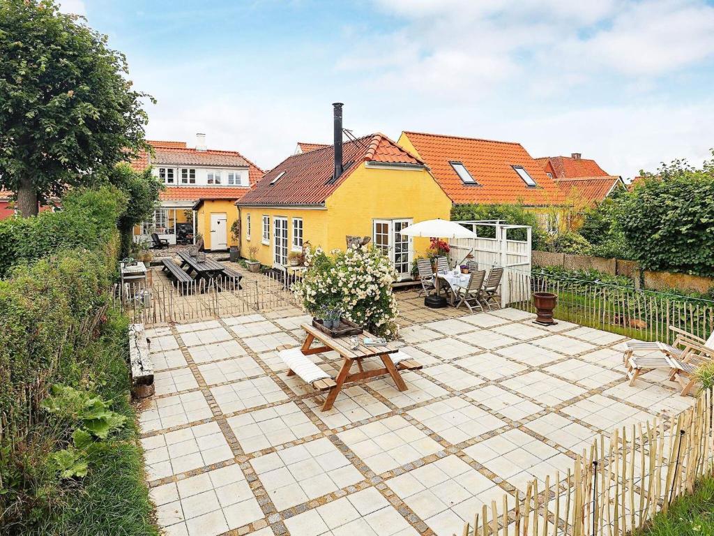 賽比的住宿－4 person holiday home in S by，一个带桌椅的庭院和一座黄色的房子