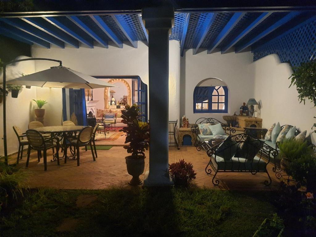 布茲尼蓋的住宿－Villa à Bouznika Bay-plage et golf，庭院配有桌椅和遮阳伞。