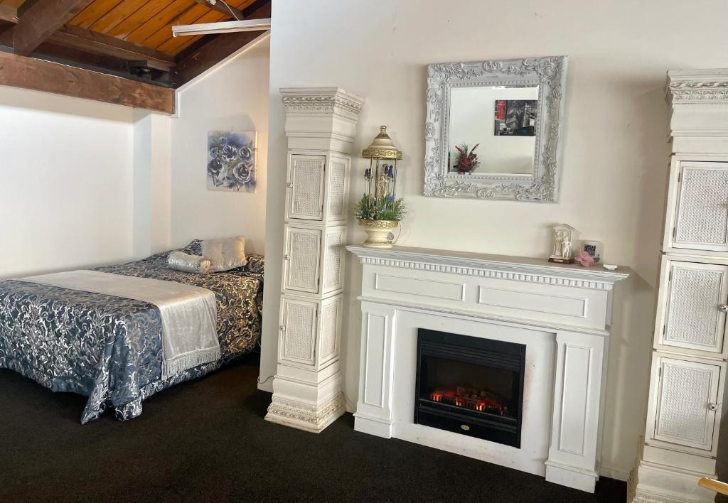 a bedroom with a fireplace and a bed and a mirror at Kamo Studio Apartment in Whangarei