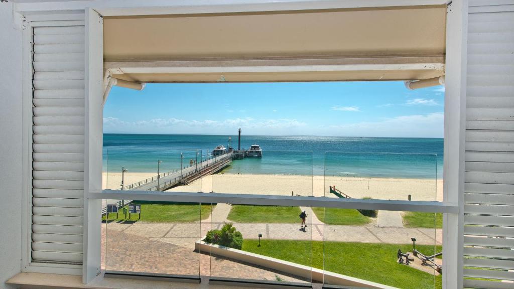 een raam met uitzicht op een strand en een pier bij Deep Blue Apartment 8 in Tangalooma