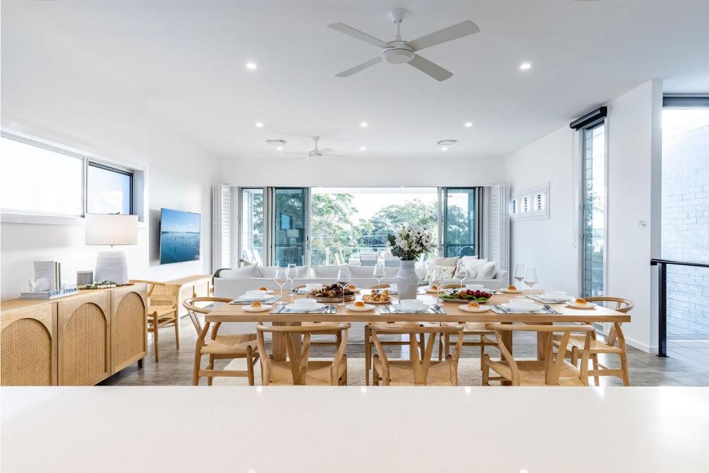 a dining room and living room with a table and chairs at Sunset Jewel - 7a Cromarty Road, Soldiers Point - Ocean Views, Breathtaking Sunsets, Linen, AIR CON & Wi-Fi in Soldiers Point