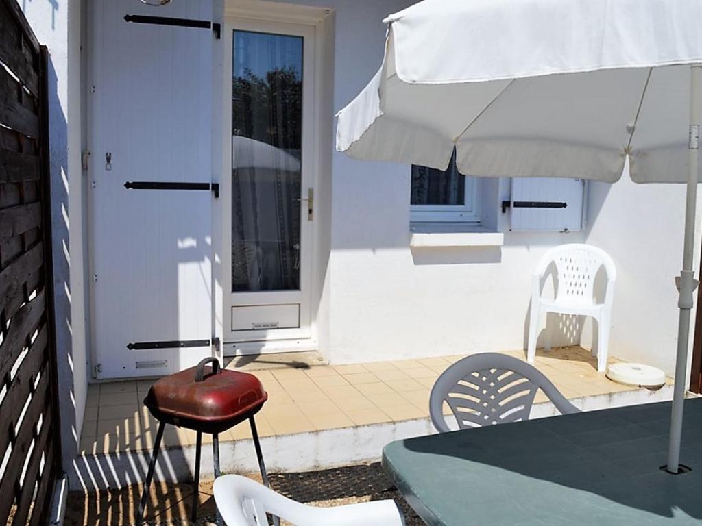 une terrasse avec une table, une chaise et un parasol dans l'établissement Petit Duplex Centre-Ville, Près Plage, Terrasse, Parking, Animaux Acceptés - FR-1-22-244, à La Tranche-sur-Mer