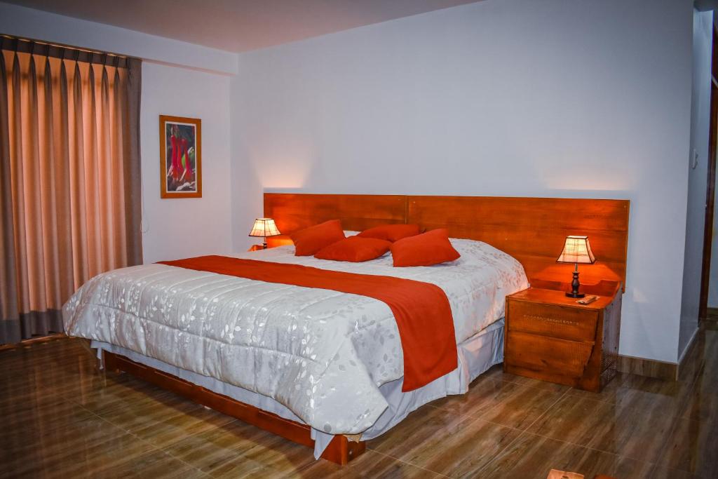 1 dormitorio con 1 cama grande con almohadas rojas en CASA TALIOS, en Carhuaz