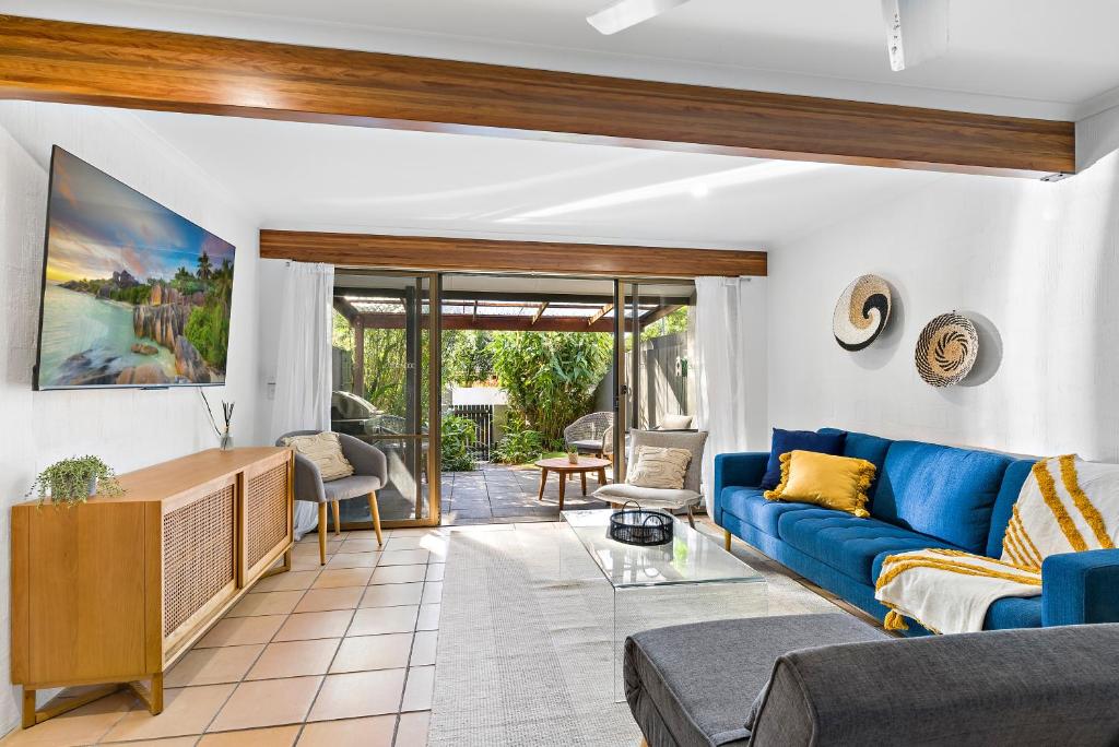 a living room with a blue couch and a table at Stylish Townhouse, private courtyard walk to beach in Noosaville