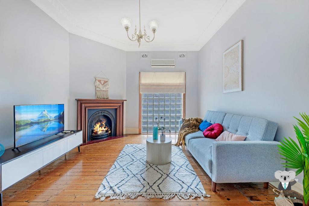 ein Wohnzimmer mit einem Sofa und einem Kamin in der Unterkunft KOZYGURU Campsie Oldie-but-goodie look 4 Bed House NCA011 in Sydney
