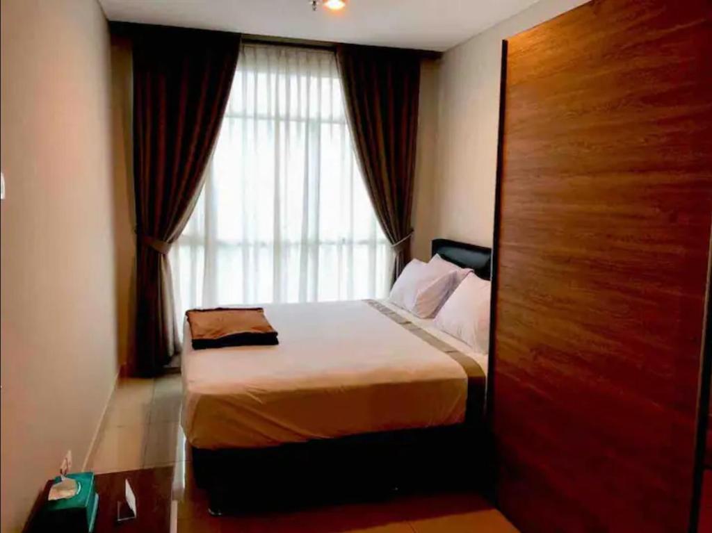 a bedroom with a bed in front of a window at Central Park Residence in Jakarta