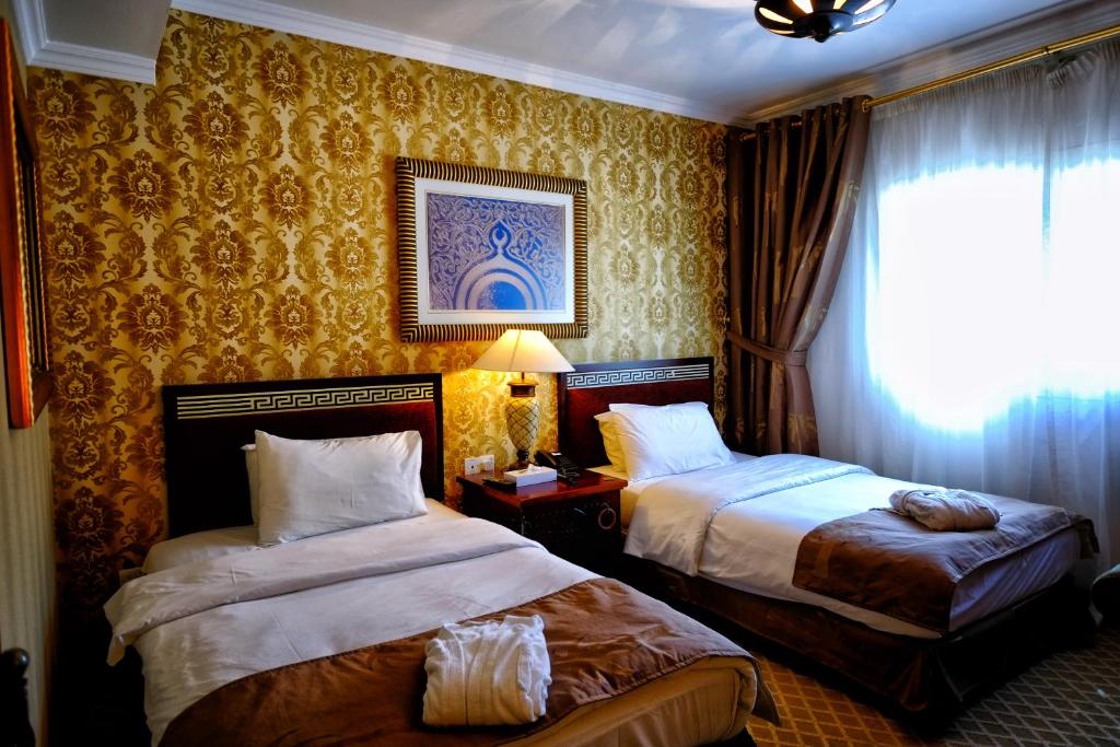 a hotel room with two beds and a window at Sharjah International Airport Hotel in Sharjah