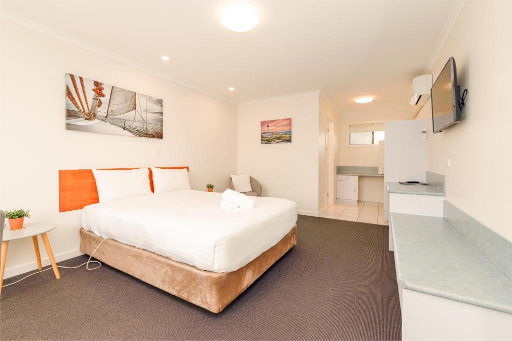 1 dormitorio blanco con 1 cama y TV en Seasonal South Motel & Function Centre, en Ulverstone