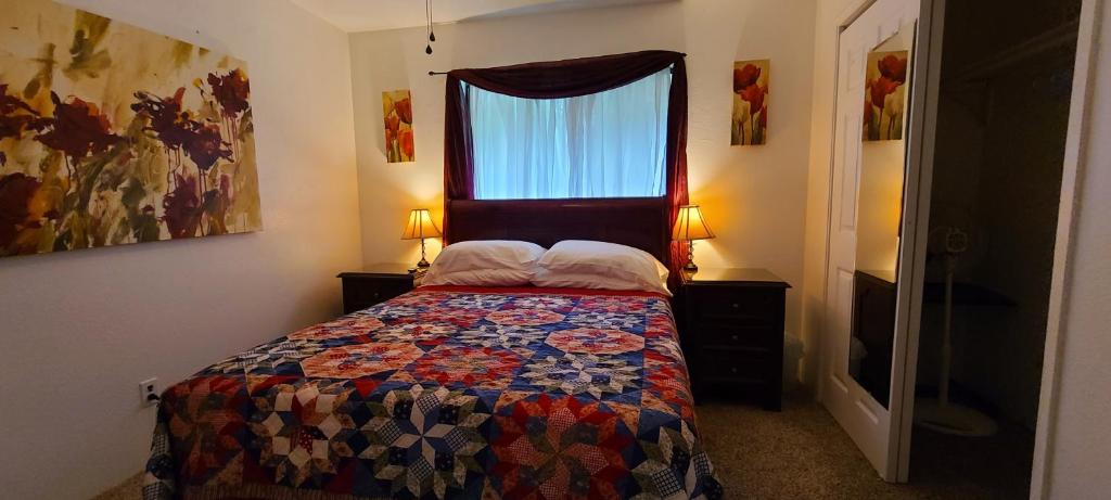 a bedroom with a bed with a quilt and a window at Humble Home in Hawaii in Ainaloa