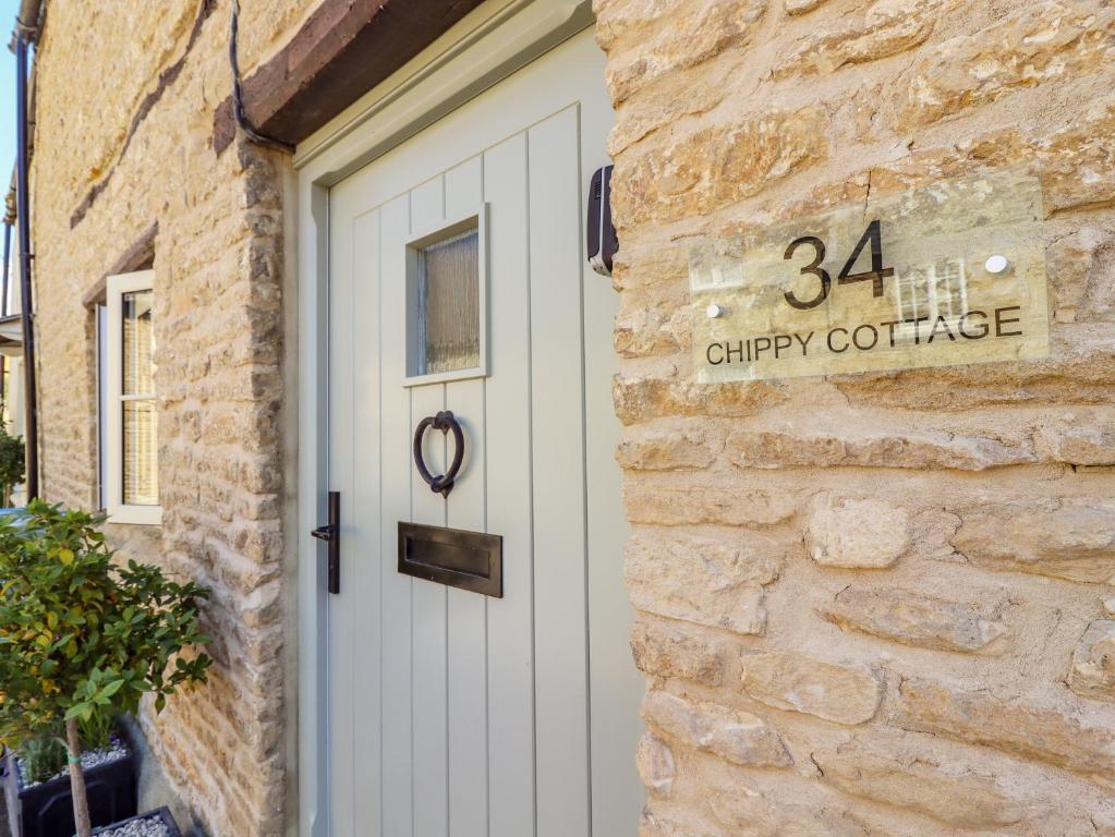 a white door on a brick building with a sign on it at Chippy Cottage in Chipping Norton