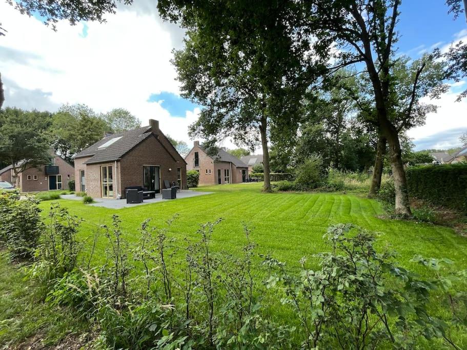 a large yard with a house in the background at sfeervol vrijstaand huisje 6 persoons ruime tuin, centraal bij Nijmegen in Ewijk