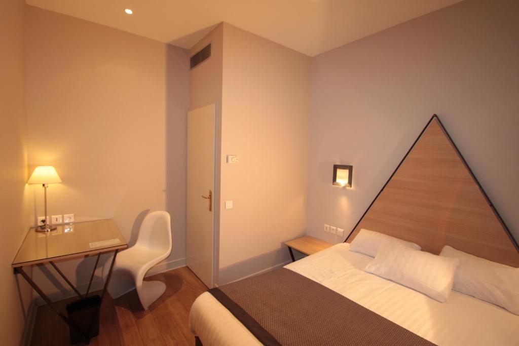 a bedroom with a bed and a desk and a table at Hôtel Amirauté in Toulon
