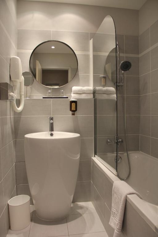 a bathroom with a toilet and a shower and a mirror at Hôtel Amirauté in Toulon