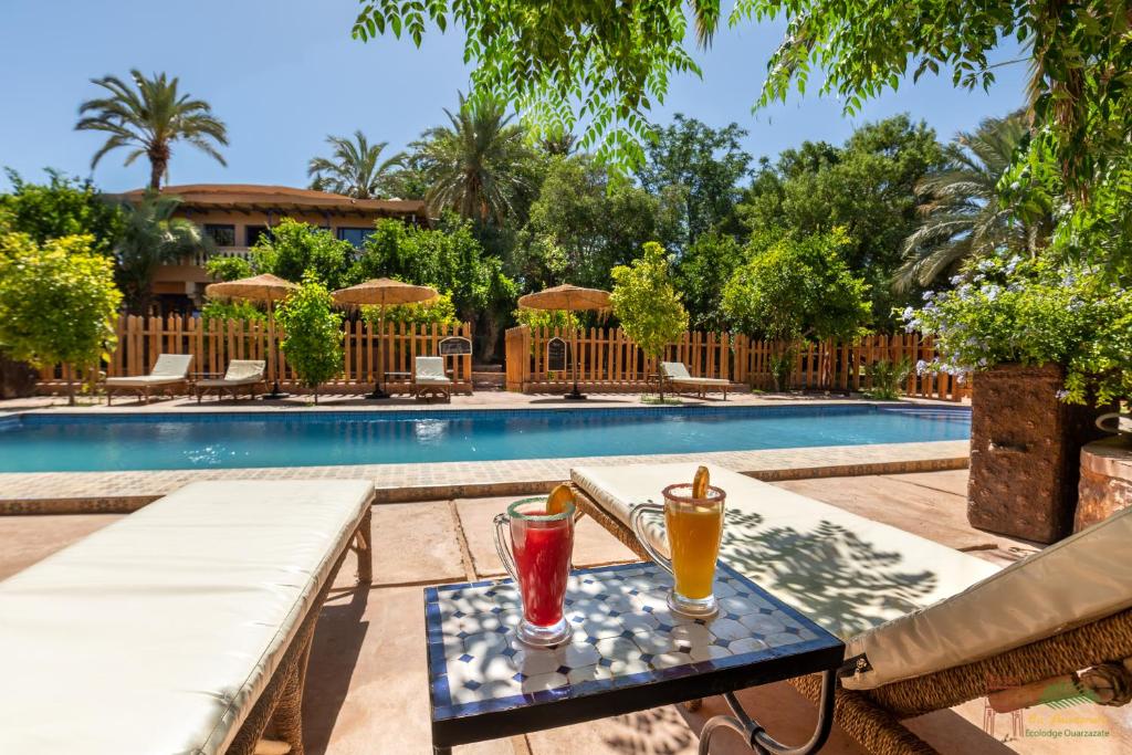 - une table avec deux boissons à côté de la piscine dans l'établissement Ecolodge La Palmeraie, à Ouarzazate