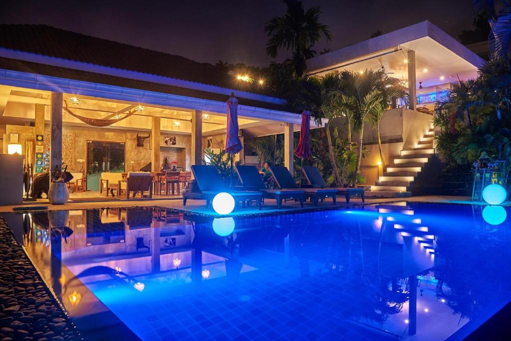 a swimming pool in front of a house at night at Baan Sawan Samui Resort in Chaweng Noi Beach