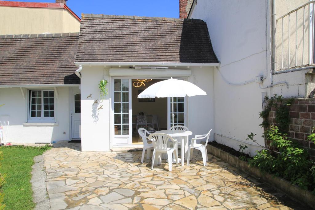 a white house with a table and an umbrella at RELAX HOME Maison et studio ensemble in Deauville