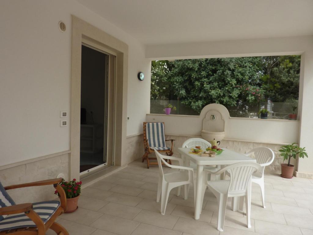 a patio with a white table and chairs and a window at Capo Scalambri in Santa Croce Camerina