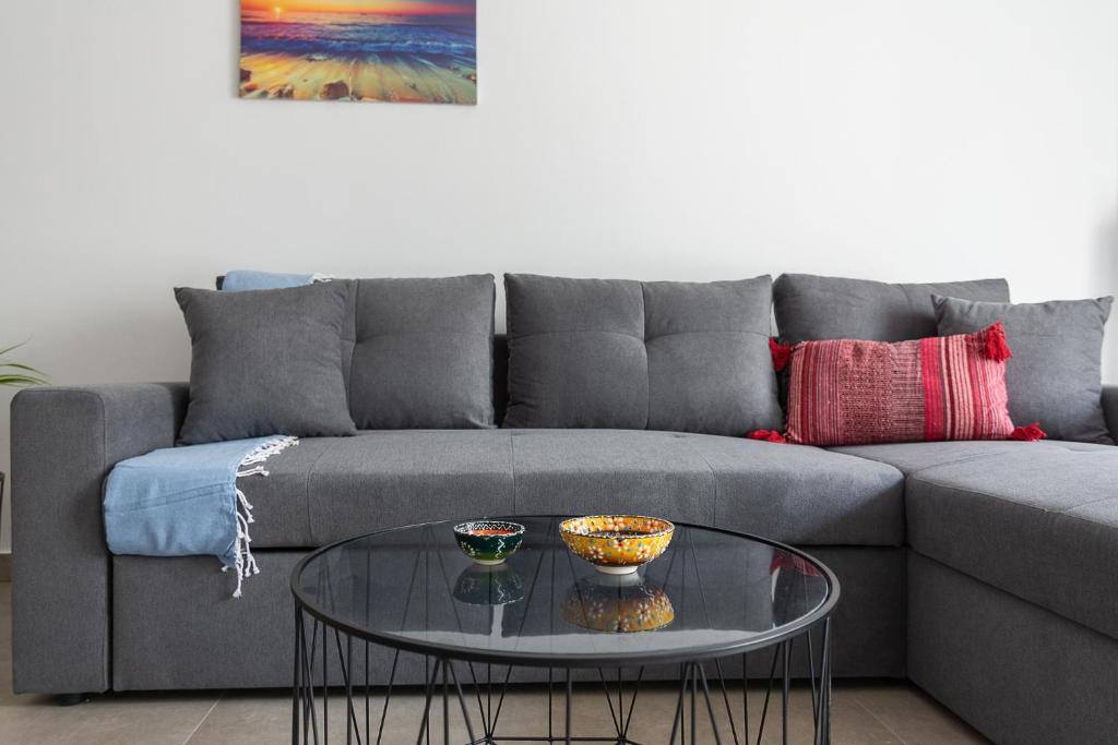 uma sala de estar com um sofá cinzento e uma mesa de vidro em Renovated Apartment next to Panathenaic Stadium em Atenas