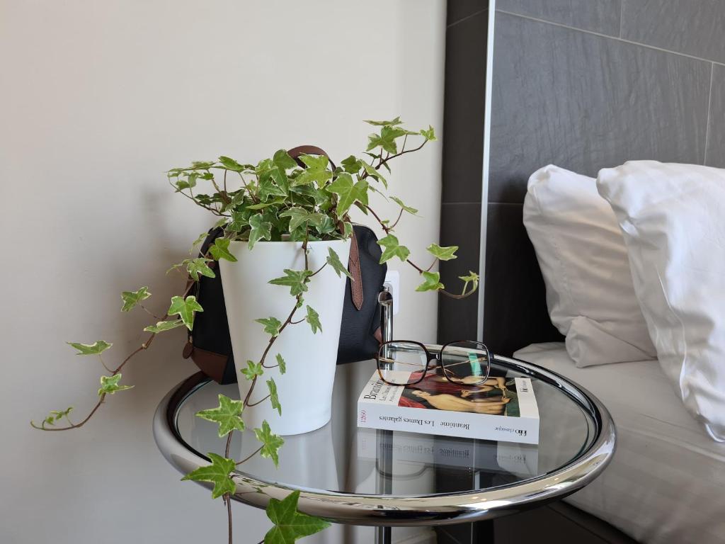 a glass table with a plant and a vase on it at Hôtel Amirauté in Toulon