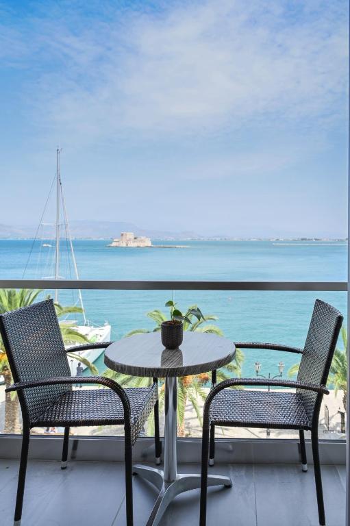 a table and chairs on a balcony with a view of the ocean at Agamemnon Hotel in Nafplio