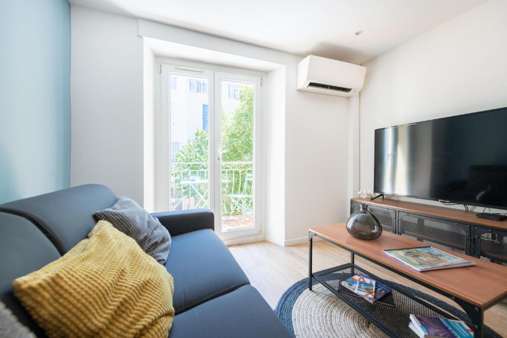 un salon avec un canapé bleu et une grande télévision dans l'établissement SUD PASSION - Ferrer Nine - cosy avec balcon, à Gardanne