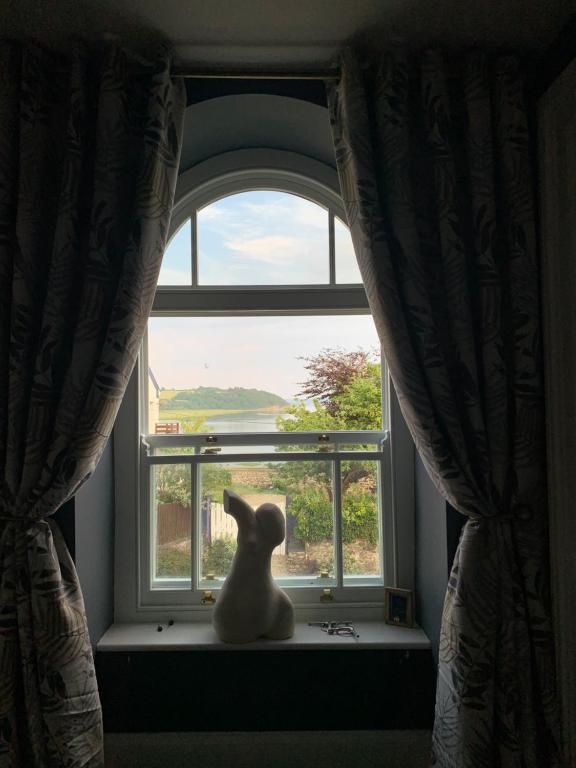 un chat assis sur un rebord de fenêtre donnant sur dans l'établissement Dylan Thomas Sea View, à Laugharne